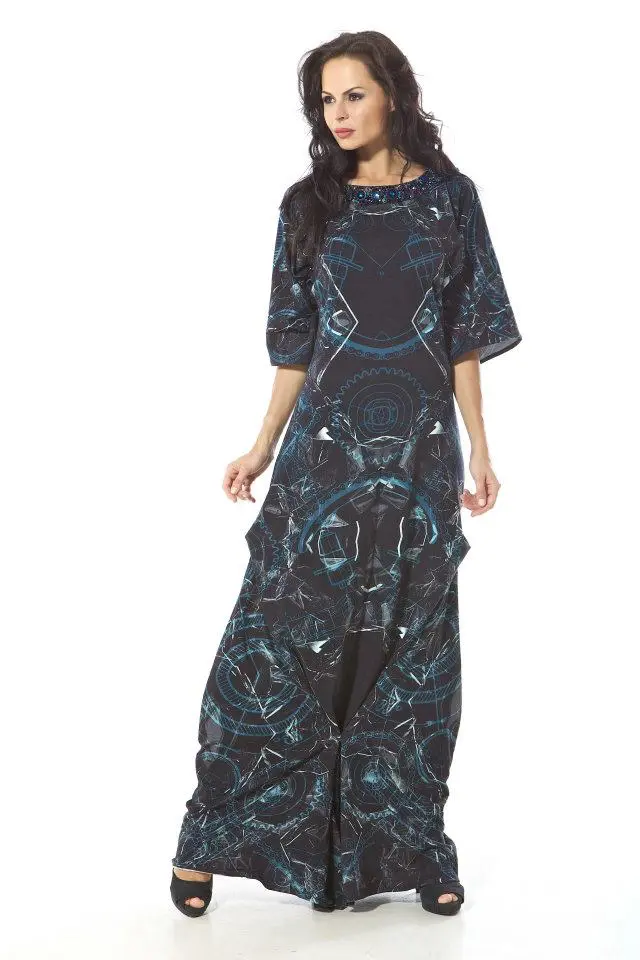 Model wearing a kimono-sleeve cotton dress pleated at the knee, with geometric and glass-inspired prints in black, grey, and blue tones.